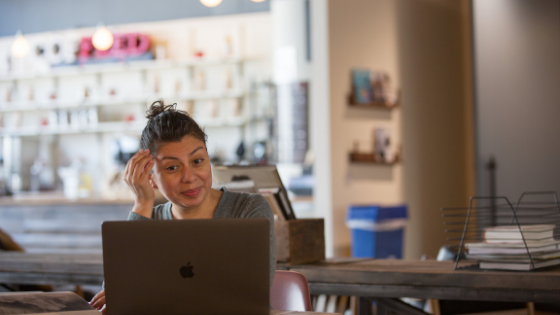 A woman uses sign language in a video conference call in a coffee shop